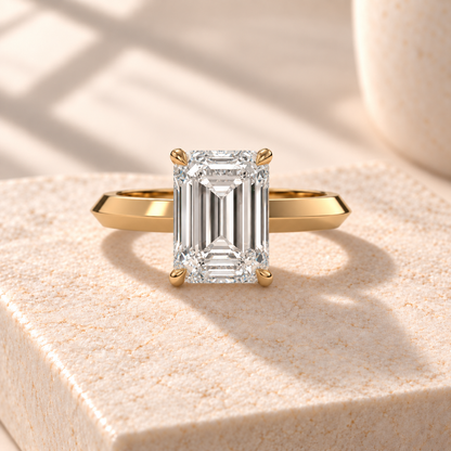 Veyra emerald-cut solitaire in yellow gold, front design preview on cream marble