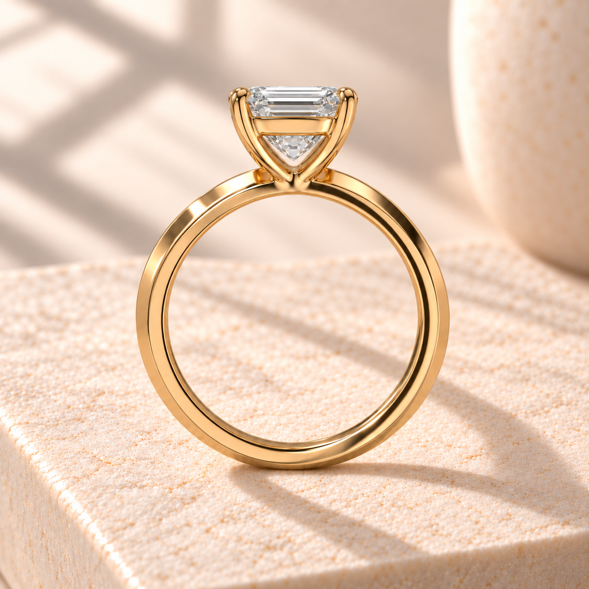 Veyra emerald-cut knife-edge solitaire in yellow gold, side design preview on cream marble