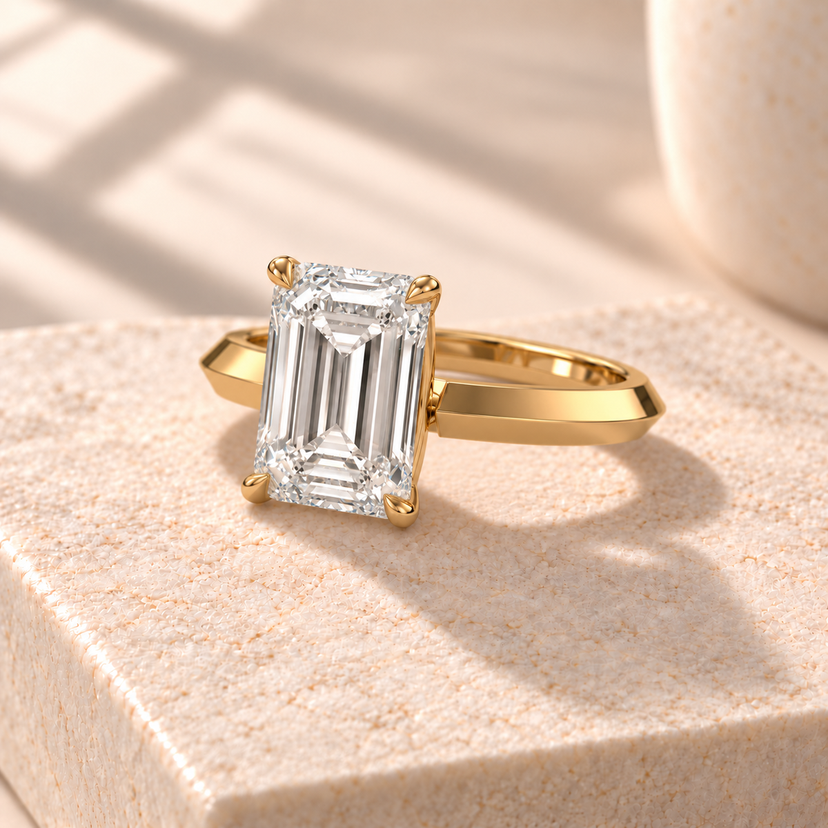 Veyra emerald-cut knife-edge solitaire in yellow gold, three-quarter design preview on cream marble