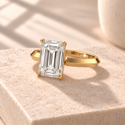 Veyra emerald-cut knife-edge solitaire in yellow gold, three-quarter design preview on cream marble
